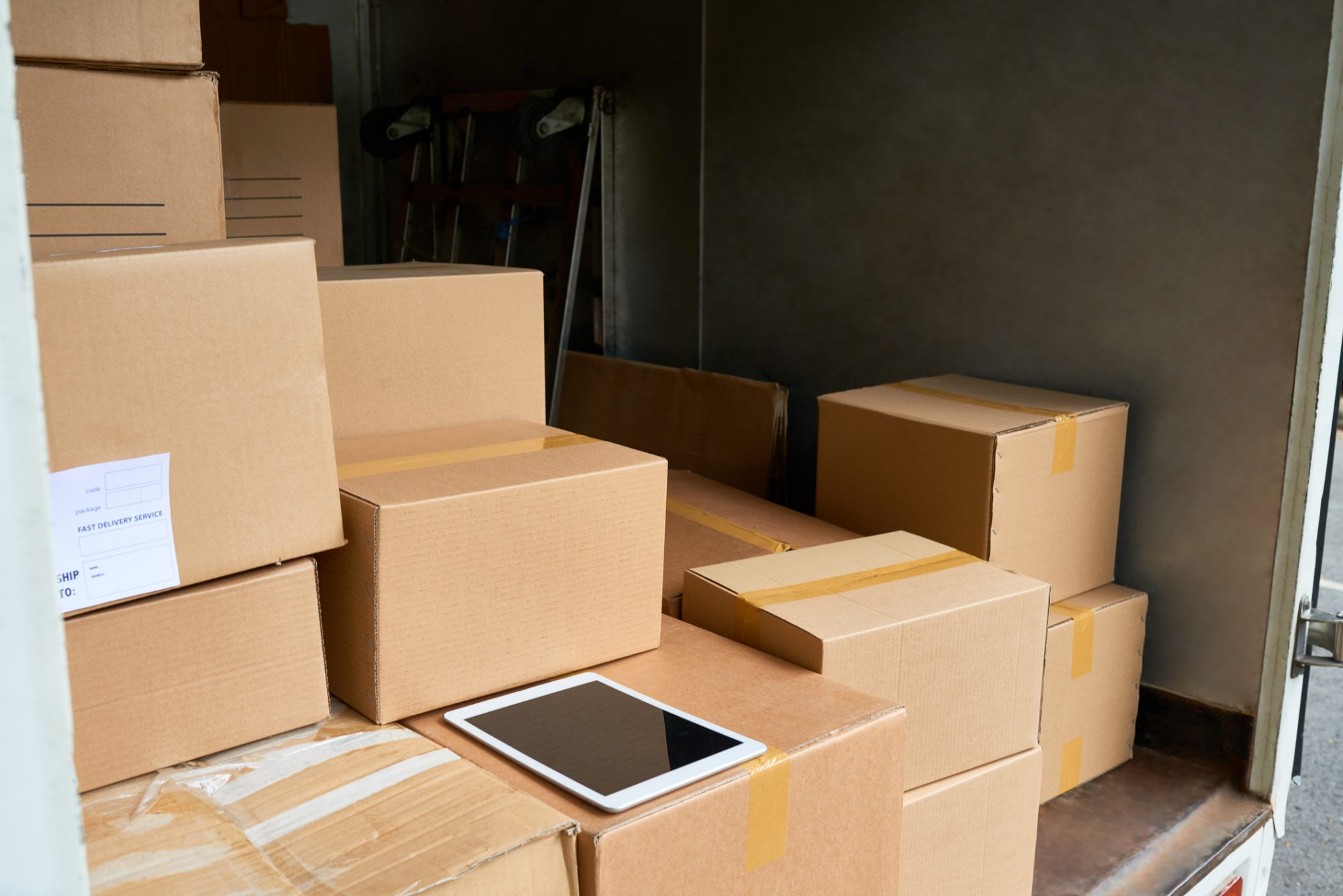 Many cardboard boxes and digital tablet insite delivery truck